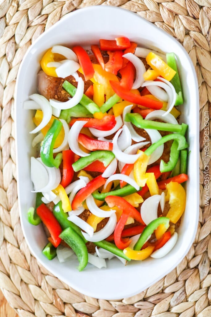 How to make baked chicken fajitas in oven step 2: Cover chicken with sliced bell pepper and onion.