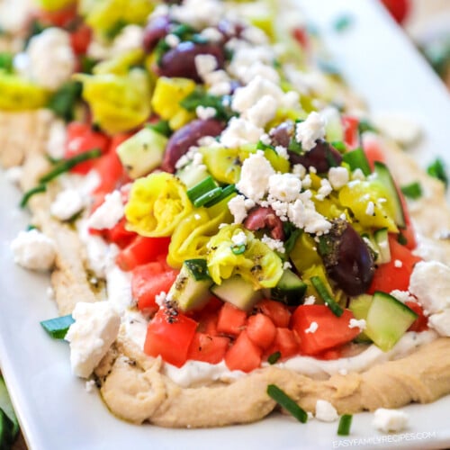 Layered Greek Dip Recipe prepared on a platter for a party.