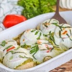 baked caprese chicken garnished with basil being served out of a casserole dish