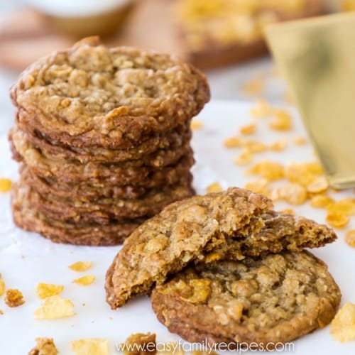 Cornflake cookies piled up with one cookie broken in half in the front