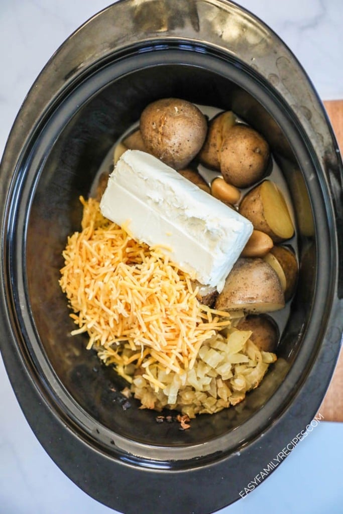How to make crockpot baked potato soup step 2: Add cream cheese and cheddar cheese to the slow cooker and allow the cream cheese to soften.