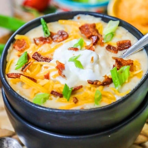 Close up of crockpot baked potato soup served in a bowl with cheese sour cream bacon and chives.
