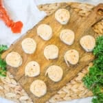 buffalo chicken roll ups on a wooden tray and vegetables around the tray