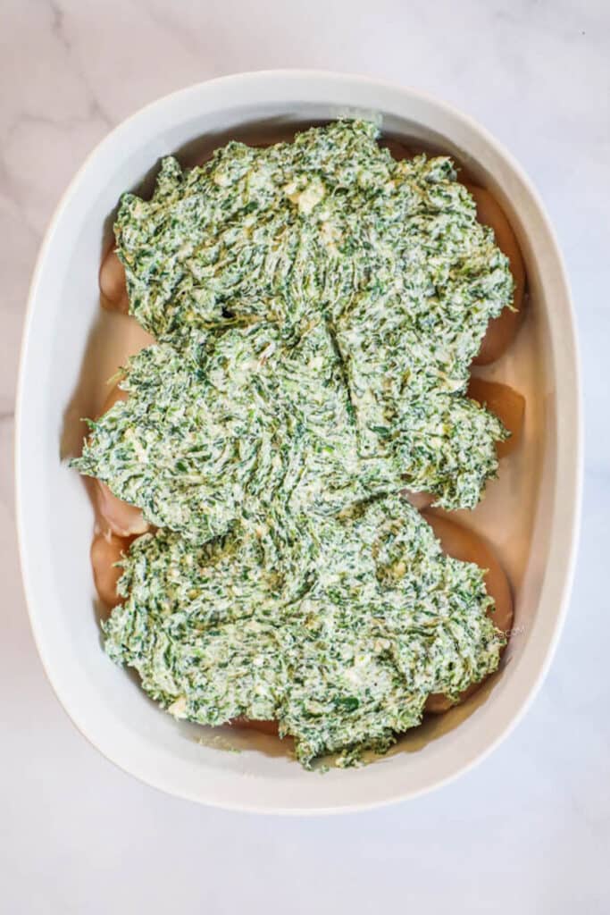 How to make Spinach and Feta Chicken Step 2: Place chicken breast in baking dish and spread spinach feta cheese mixture over top of chicken.