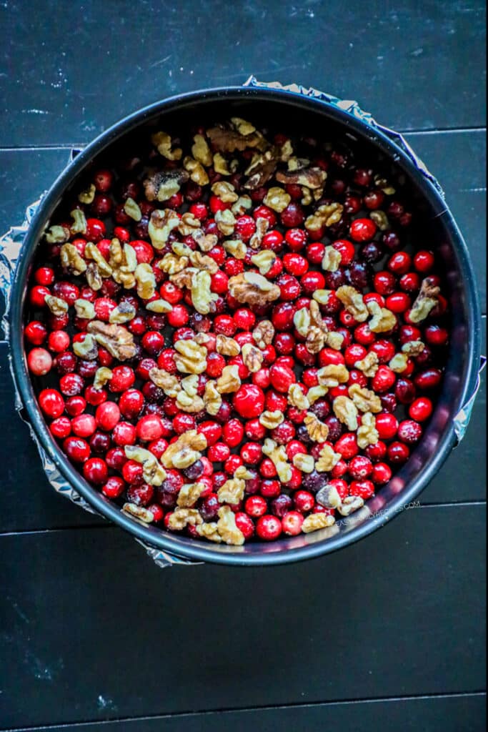 How to make Cranberry Cake step 2: Pour the caramel sauce in the bottom of the pan and then cover with cranberries and nuts.