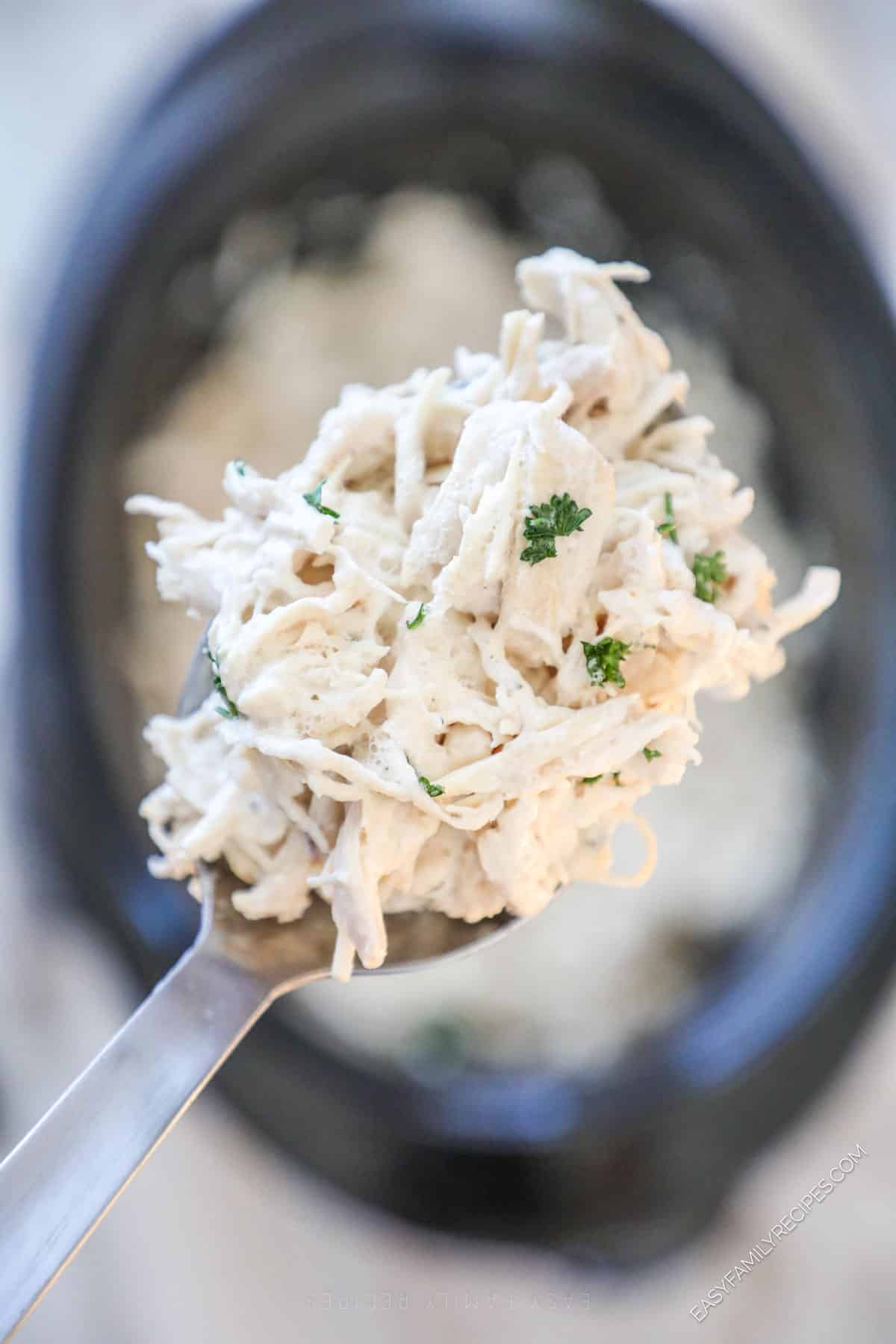 Slow cooker Ranch Chicken being lifted from crockpot with a spoon