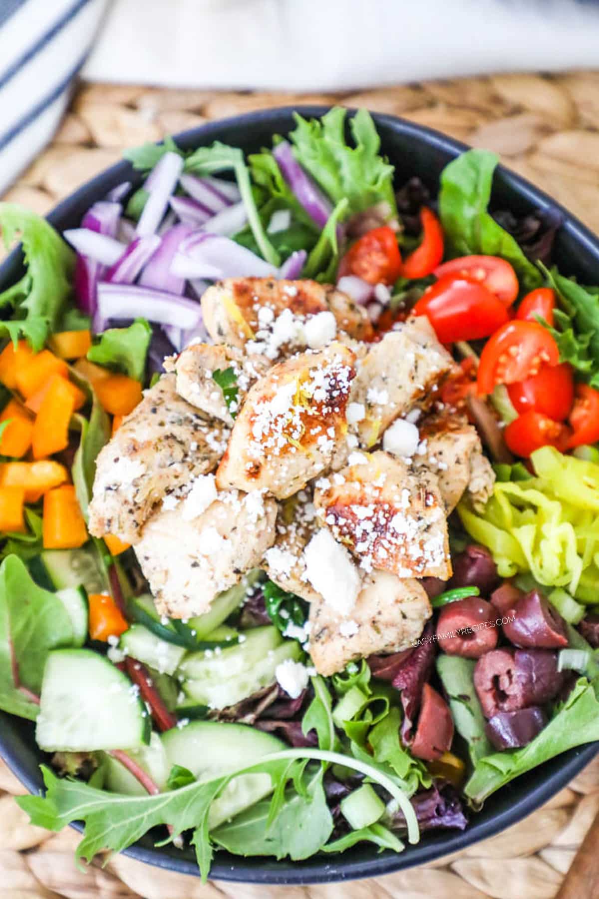 Overhead image of a salad topped with greek chicken bites.