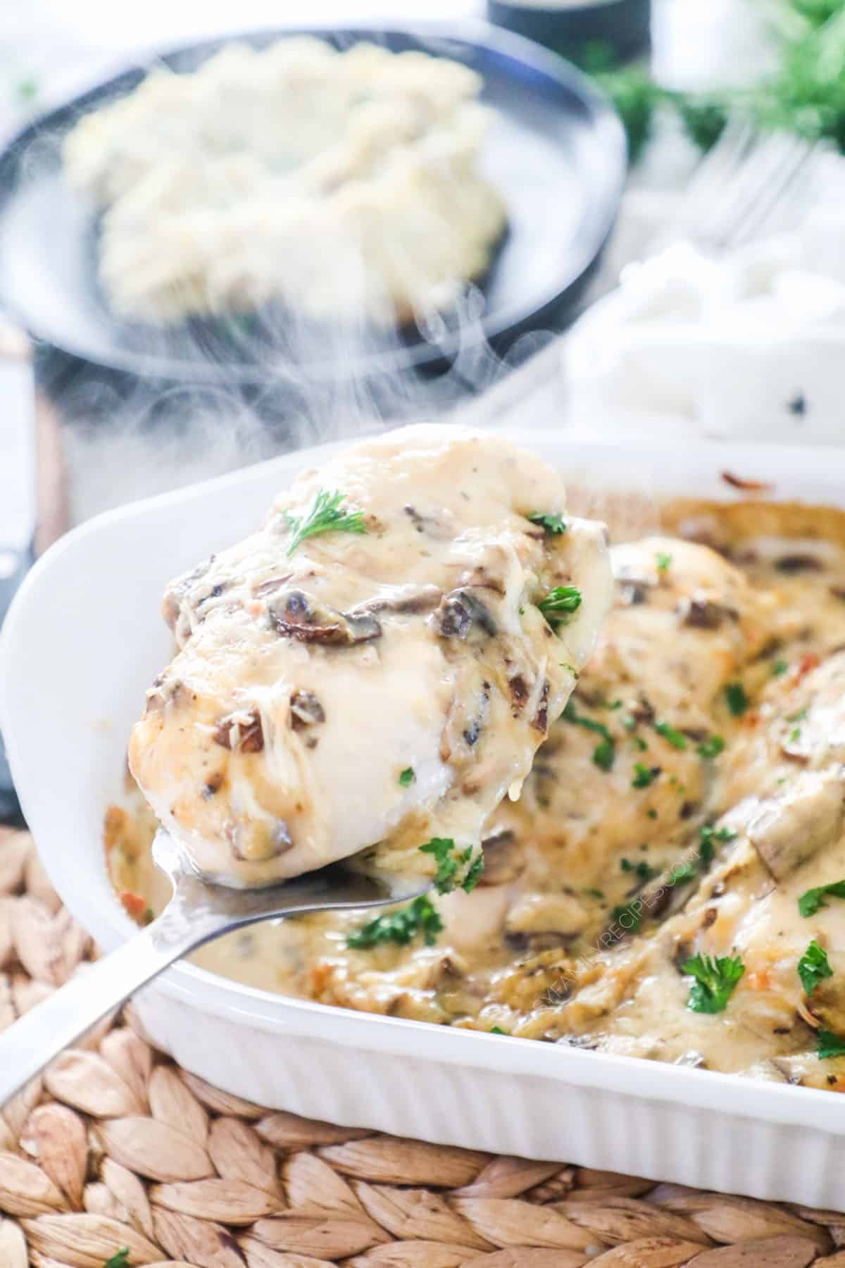 Overhead view of a baking dish with chicken breasts covered in a rich and creamy marsala sauce with mushrooms, garnished with parsley.