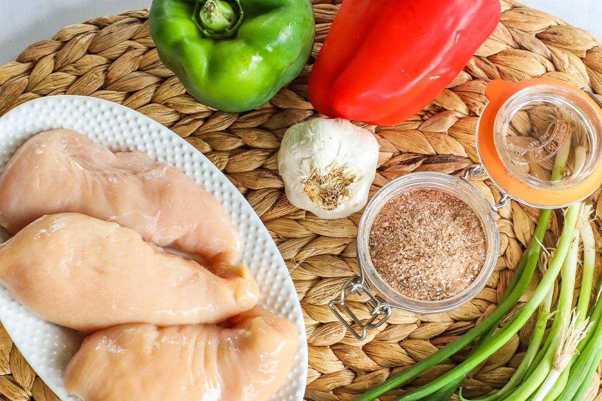 ingredients for cajun chicken skillet - chicken breast, bell peppers, cajun seasoning, olive oil, garlic, green onion