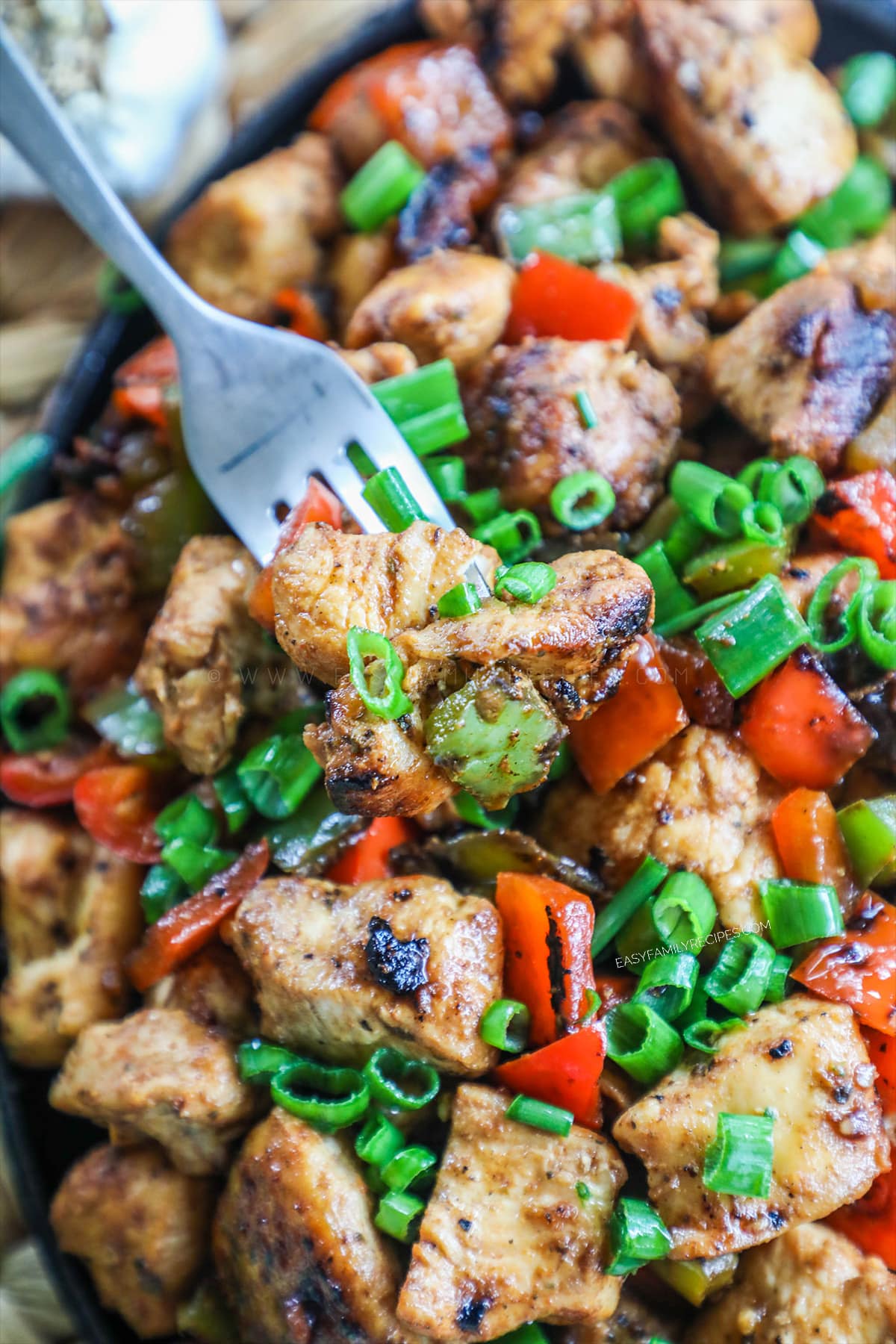 Cajun Chicken in skillet garnished with green onions and a fork