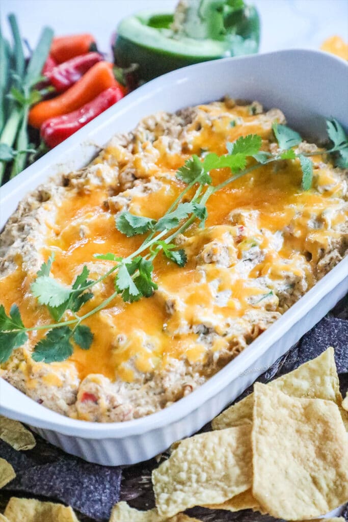 Chicken fajita dip in a baking dish with chips and veggies.