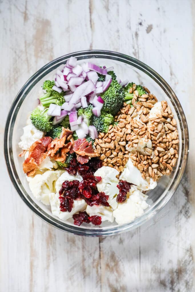 How to make Broccoli Cauliflower Salad step 2: add craisins, bacon, onion, and sunflower seeds.