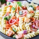 Rotini Pasta salad with pepperoni, cheese, tomatoes, and onion in a serving bowl