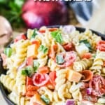 A black bowl with Rotini Salad with pepperoni, cheeses, and veggies in a bowl