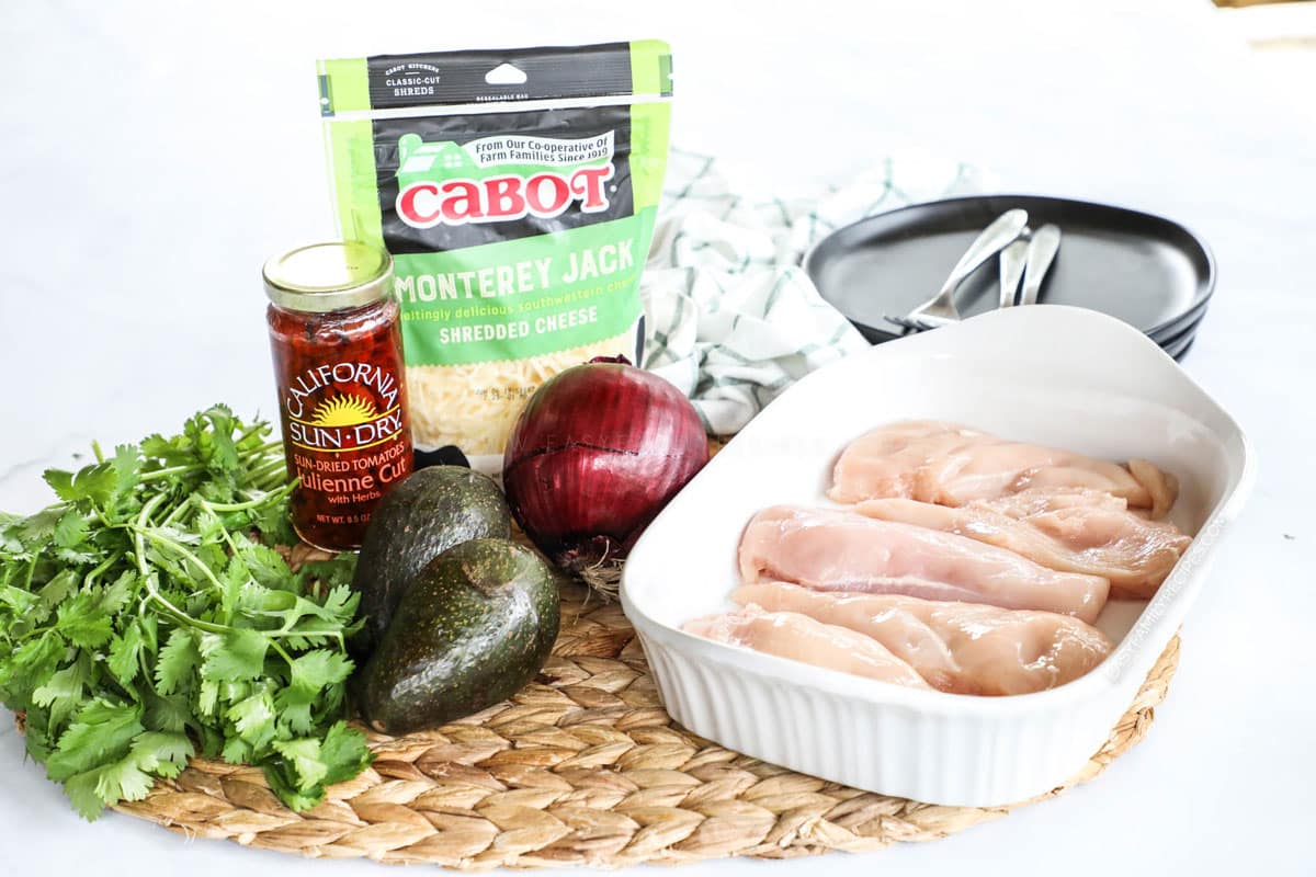 Ingredients to make Avocado Chicken including chicken breast, avocado, sun dried tomatoes, onion, cheese, and cilantro