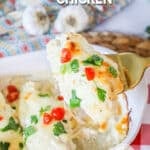 Lifting creamy garlic parmesan chicken out of the baking dish.