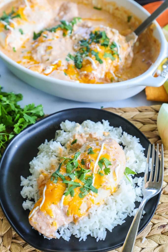 A overhead view of a baking dish with creamy salsa chicken next to a serving plate with a single chicken breast smothered with cheese on a bed of white rice.