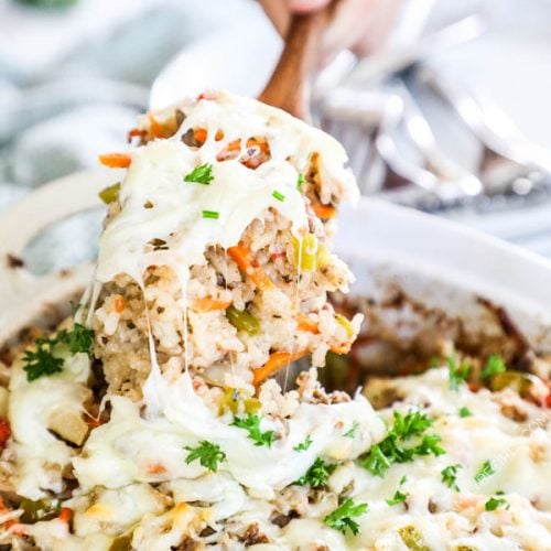 Spoon lifting out beef and rice from the casserole dish