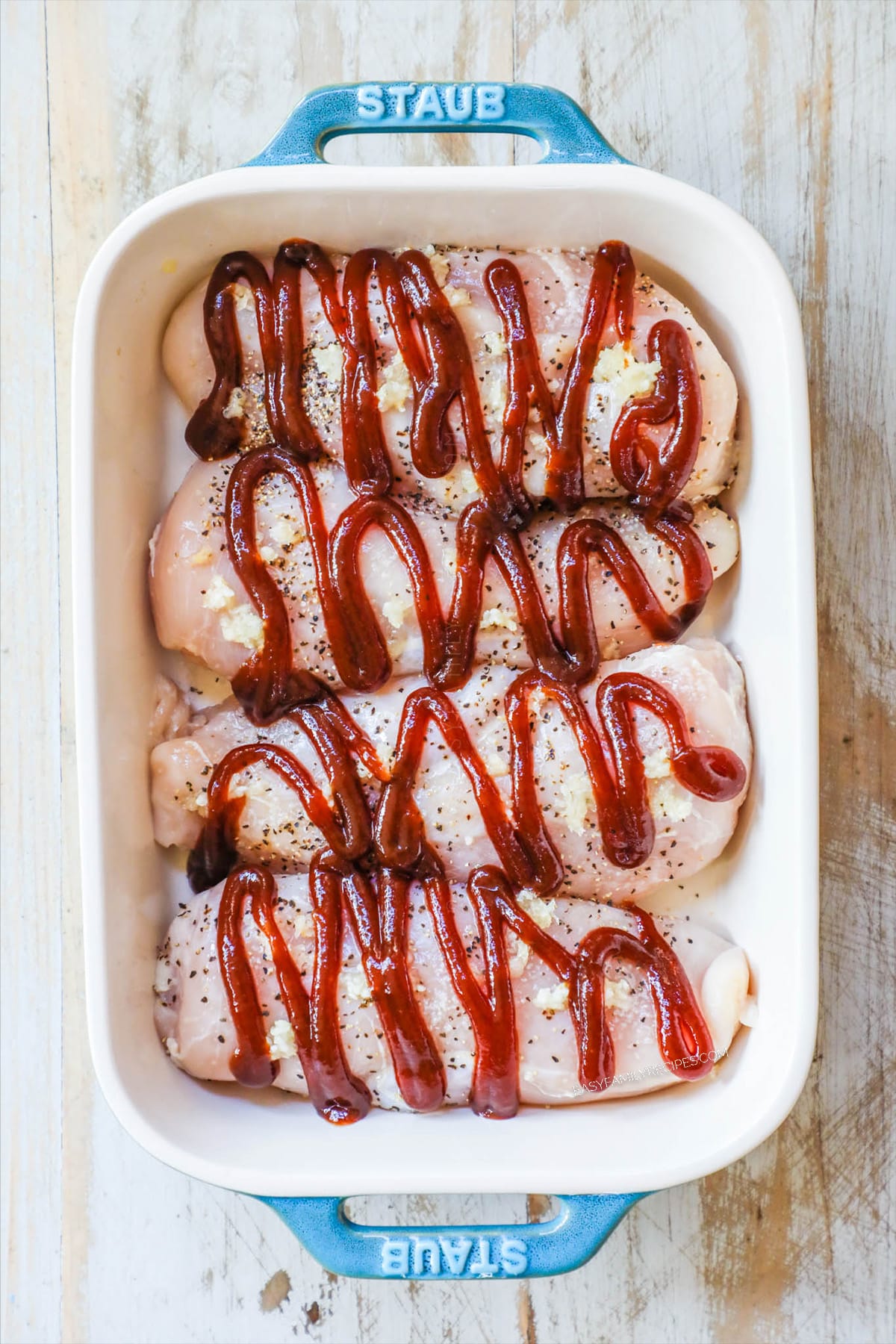 Step 2 of baked Hawaiian chicken. Chicken is in a dish with a drizzle of BBQ sauce