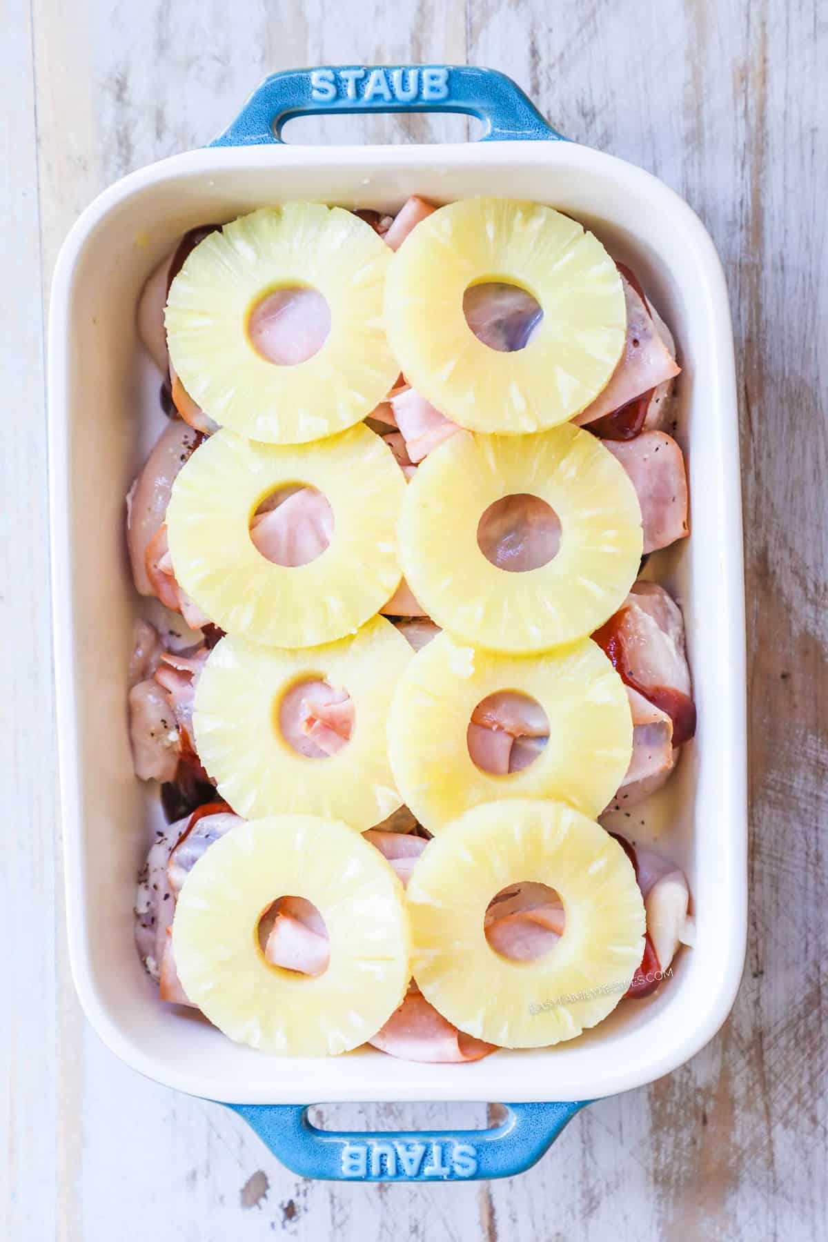 Step 4 of baked Hawaiian chicken. Chicken is in a dish with pineapple slices