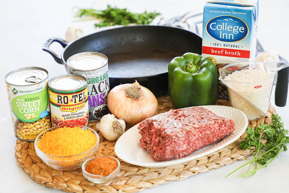 Ingredients for making Mexican Ground Beef and rice skillet including lean ground beef, rice, rotel, black beans, corn, seasoning, onion, pepper, and cheese.