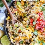 Close up of Mexican Beef and Rice skillet topped with cheese and being scooped.