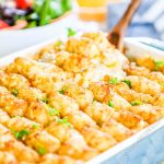 Cheesy tater tot casserole with bacon and green beans in a casserole dish with a spoon