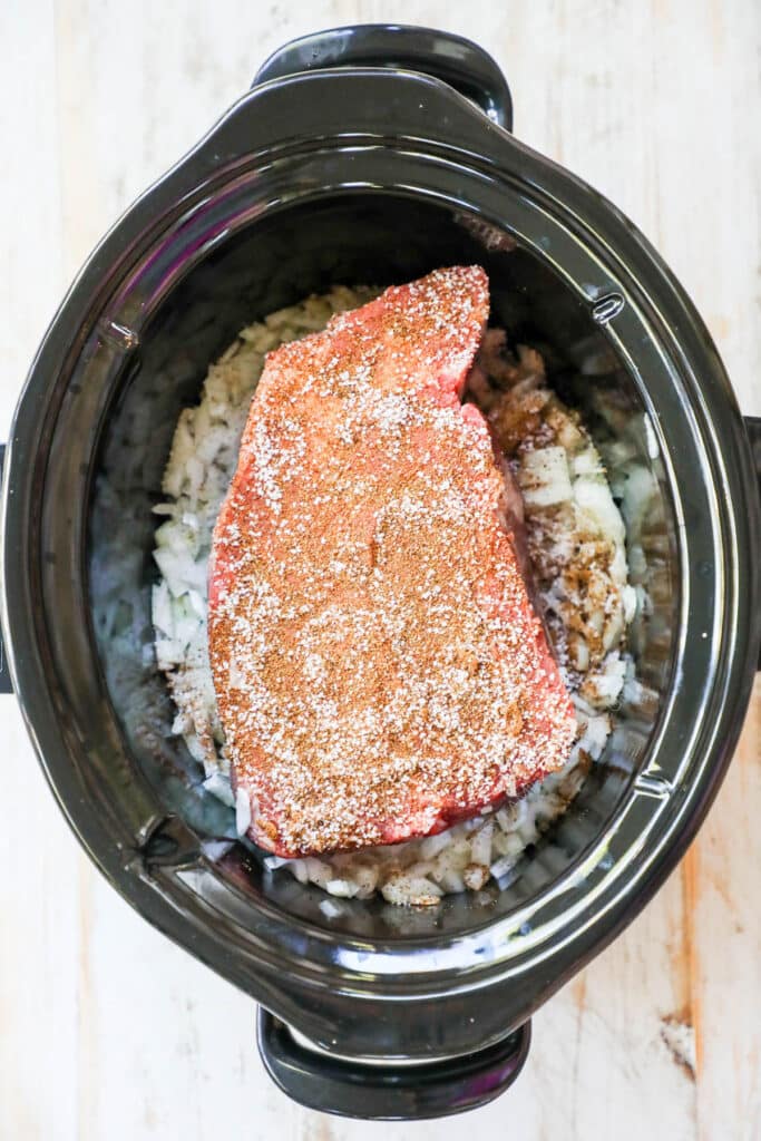 How to make Mexican Beef in crockpot step 1: Place chuck roast in slow cooker with onions and spices.