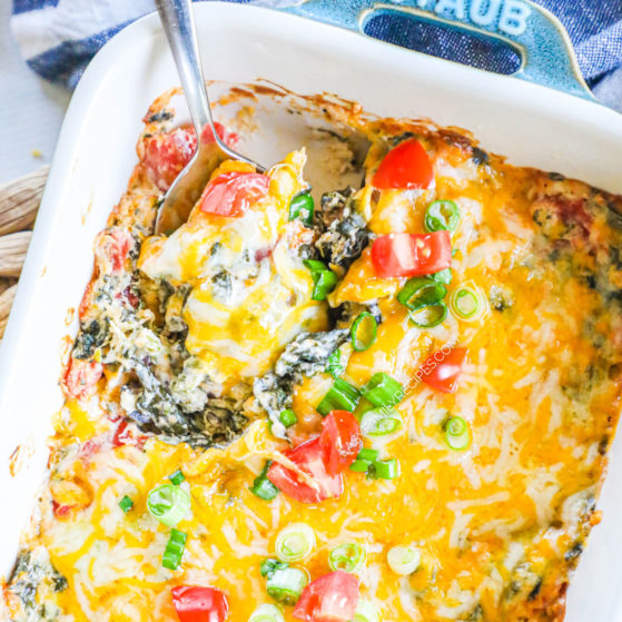 Mexican Spinach Dip baked in a casserole dish with a spoon