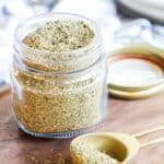 Italian Seasoning in a jar with a measuring spoon next to it