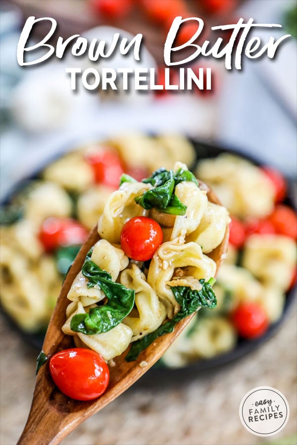 Brown Butter Tortellini with Spinach and tomatoes lifted from pot with a spoon