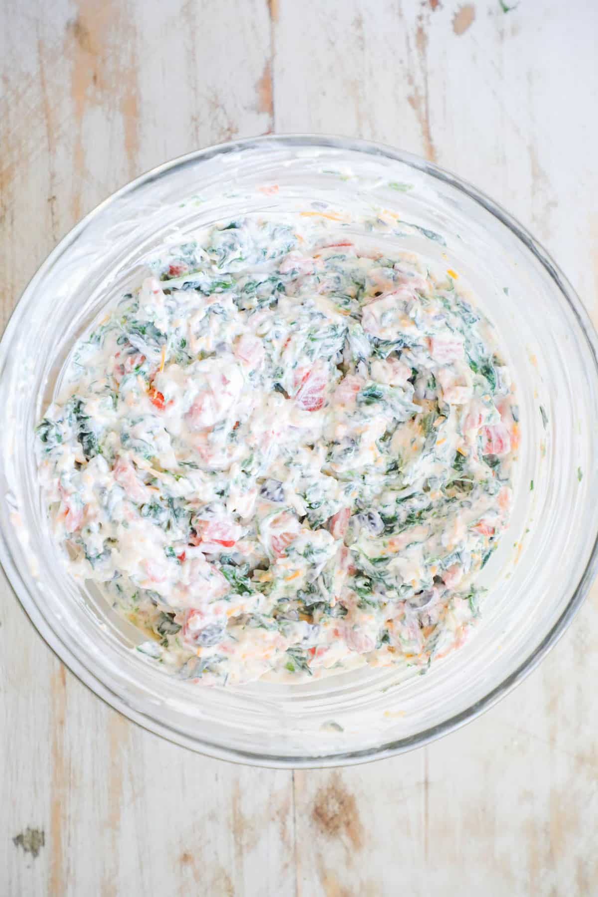 Step 2: In a large bowl mix the cream cheese and sour cream together. Stir in the Rotel tomatoes, spinach, black olives, and 1 cup colby jack cheese. Mix until combined.