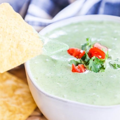 Dipping a chip into a bowl of jalapeno ranch dressing made with cilantro and tomatillo salsa
