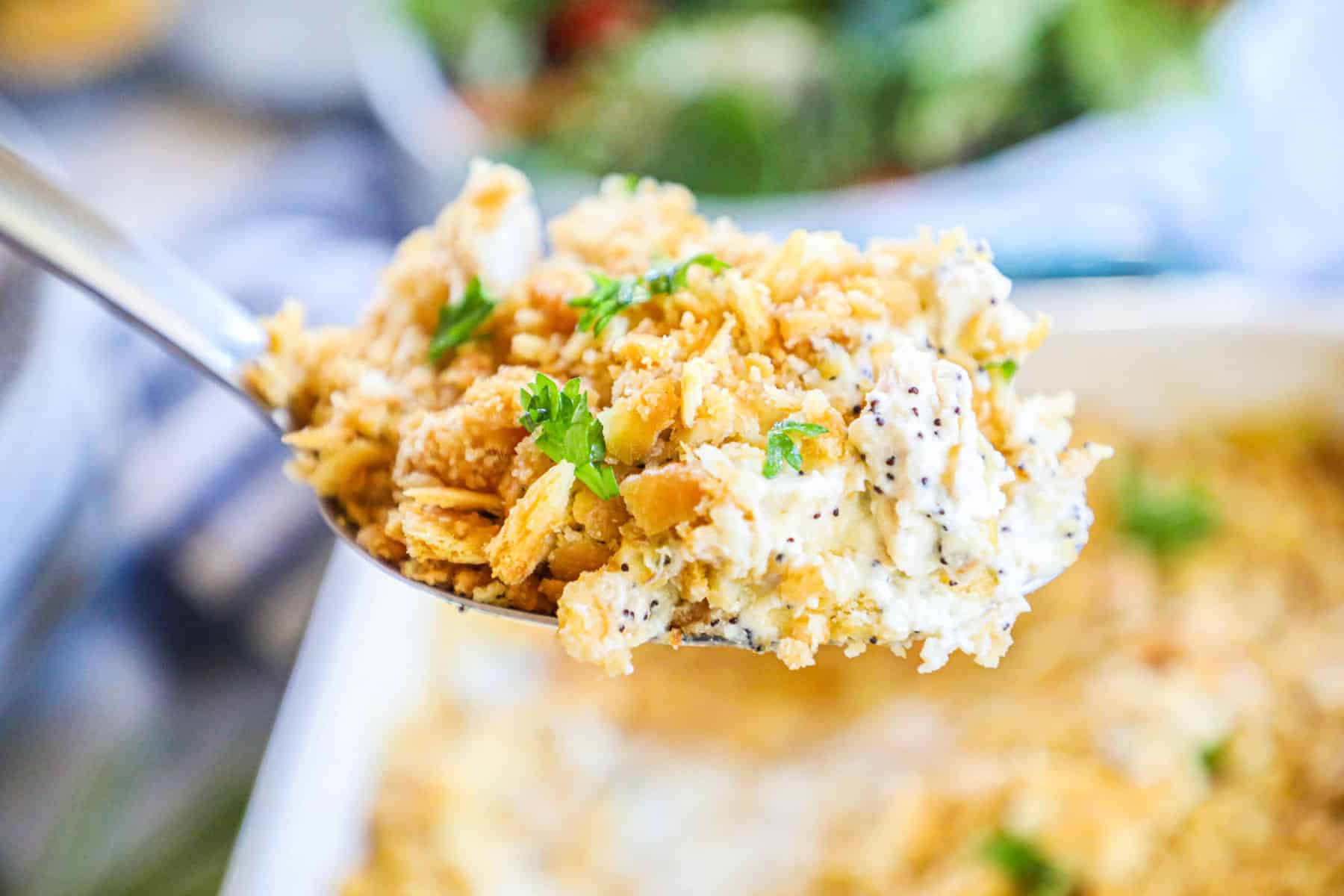 Poppy Seed Chicken being scooped out and shown with a ritz cracker topping