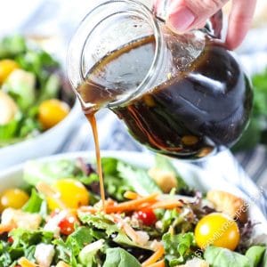 Pouring Homemade Balsamic Vinaigrette over a salad