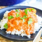 Close up of butter chicken on a plate garnished with cilantro.