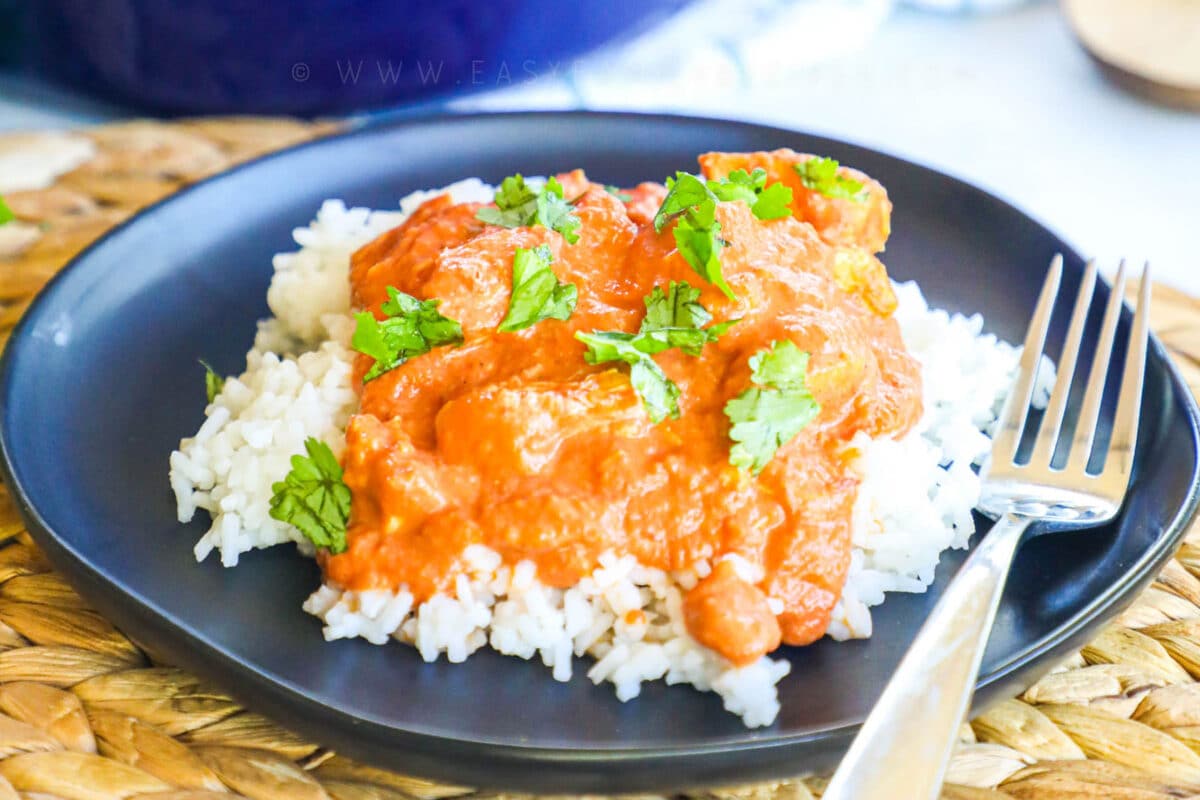 Close up of butter chicken on a plate garnished with cilantro.