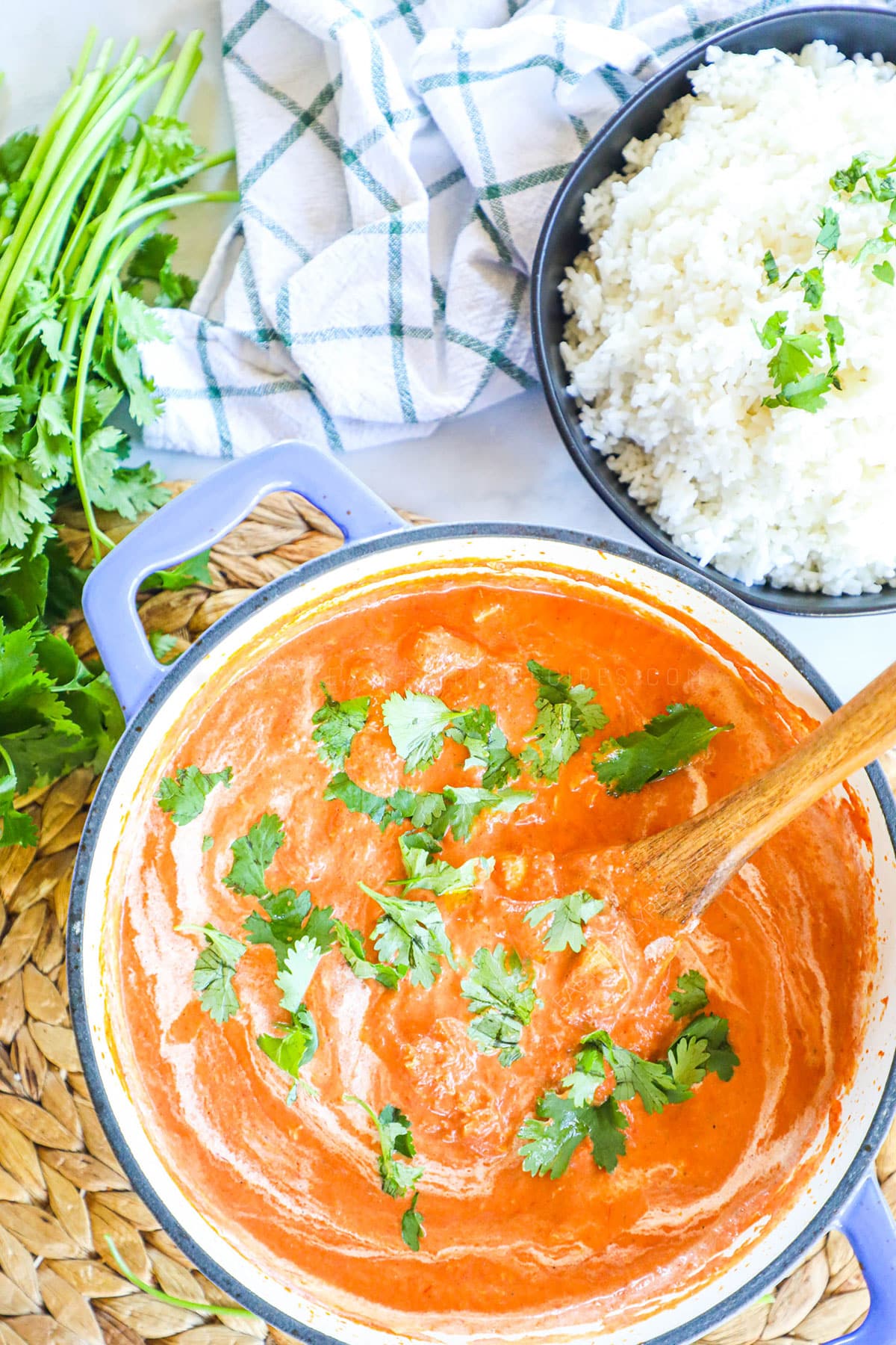 Indian Butter Chicken in a pot swirled with cream and cilantro.
