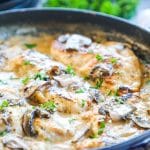 Chicken nestled in creamy mushroom sauce in a skillet and garnished with parsley