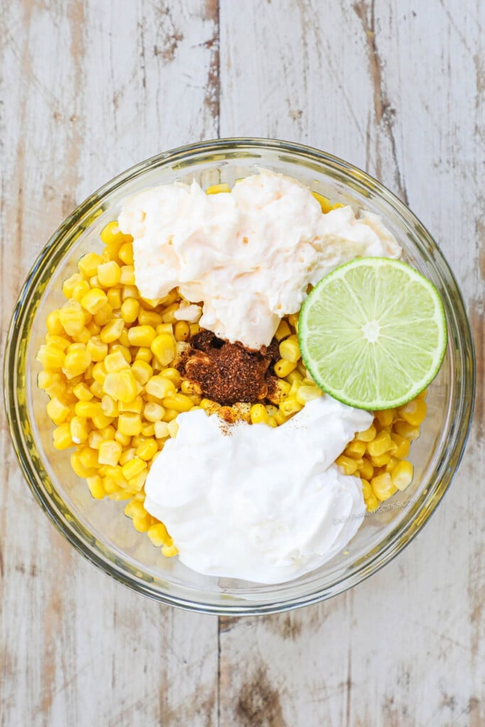 How to make Mexican Street Corn Chicken Step 2: Combine corn with mayonnaise, sour cream, seasonings, and lime to make elote topping.