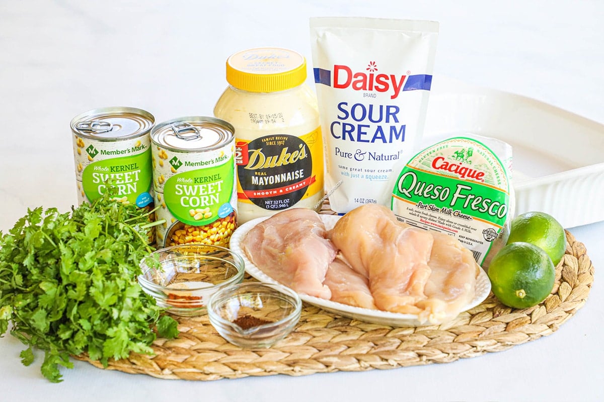 Ingredients for making elote chicken including chicken breast, corn, sour cream, mayonnaise, queso fresco and spices.