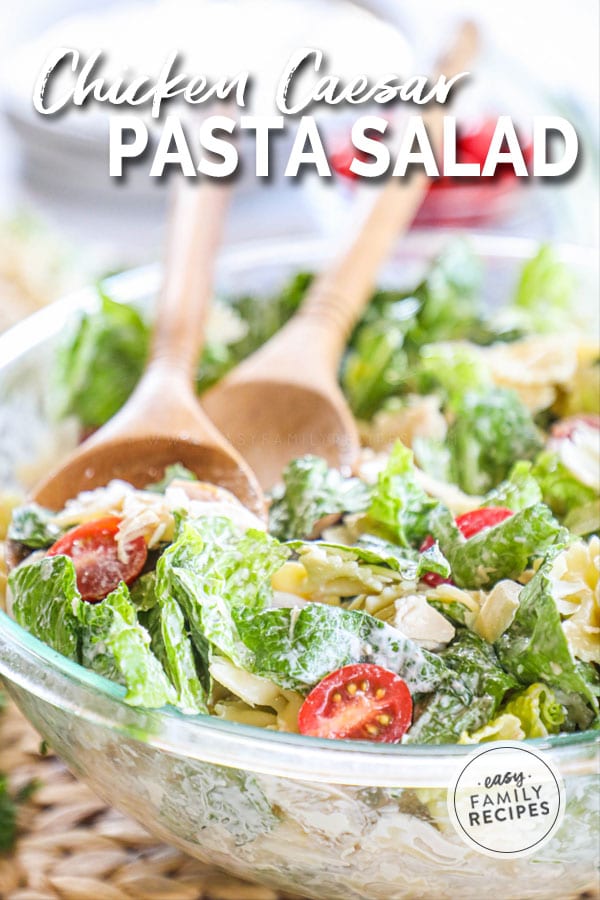 Chicken Caesar Pasta Salad in a glass bowl with wooden serving spoons