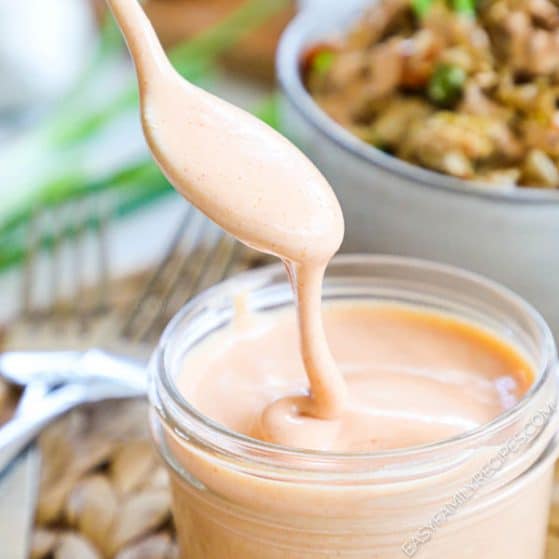 Pink Yum Yum Sauce being drizzled from a spoon into a jar
