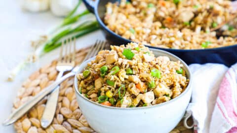 Chicken fried rice in a bowl with skillet in background