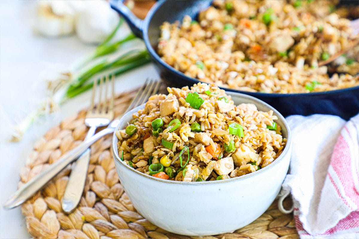 Chicken fried rice in a bowl with skillet in background