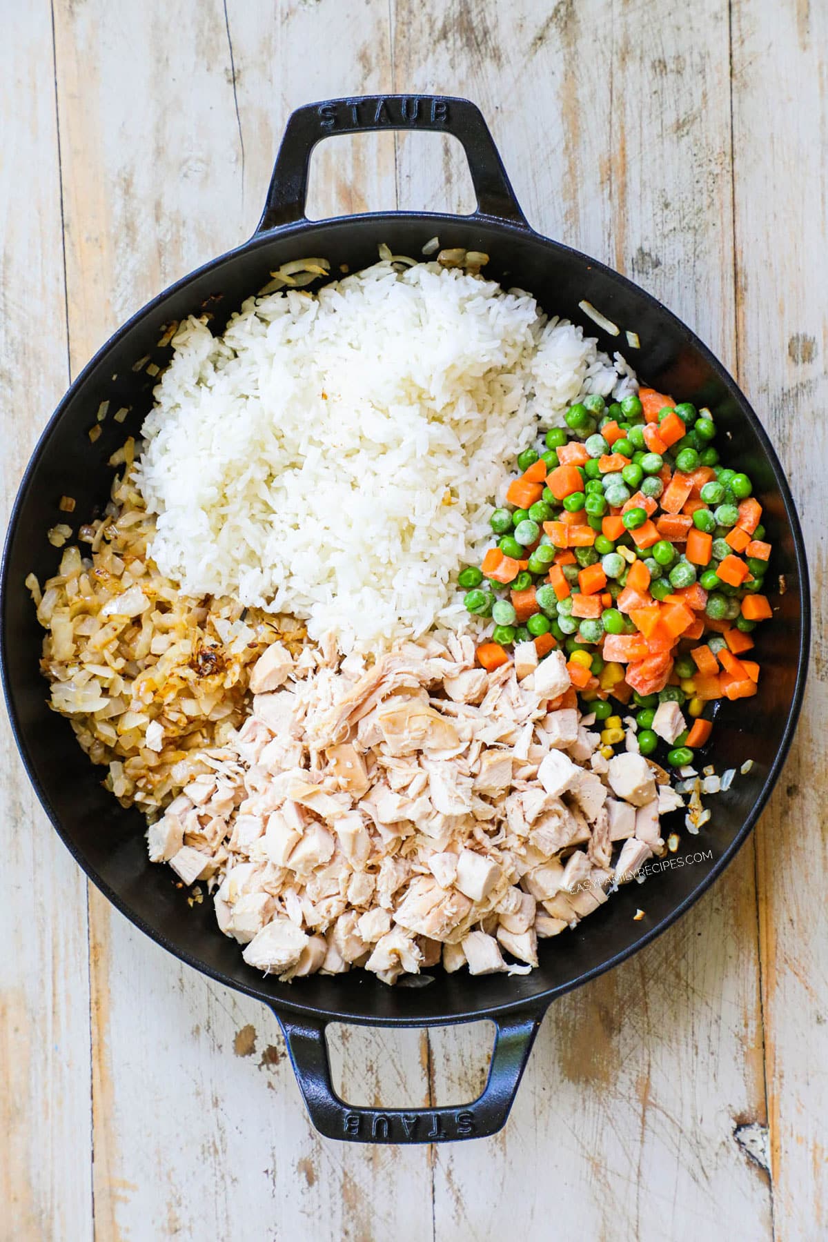 Step 2 for chicken fried rice - Add the rice, veggies, chicken, and sesame oil to the skillet and stir to combine. Let cook 3-5 minutes, then push to one side