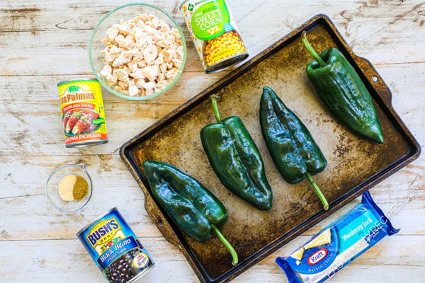 Ingredients for chicken stuffed poblano peppers, including rotisserie chicken, corn, black beans, enchilada sauce, cheese and poblano peppers