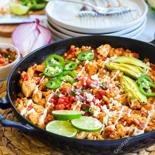 Chicken and Cauliflower rice burrito bowl in pan topped with avocado, lime and pico de gallo