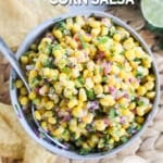 A white bowl of corn salsa and a spoon