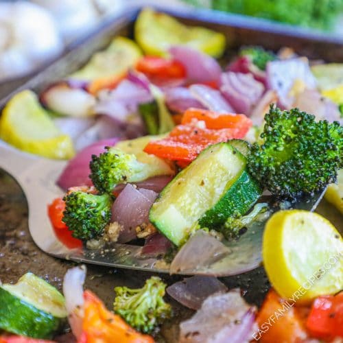 Spatula lifting oven roasted zucchini, broccoli, red pepper, onion, squash with garlic